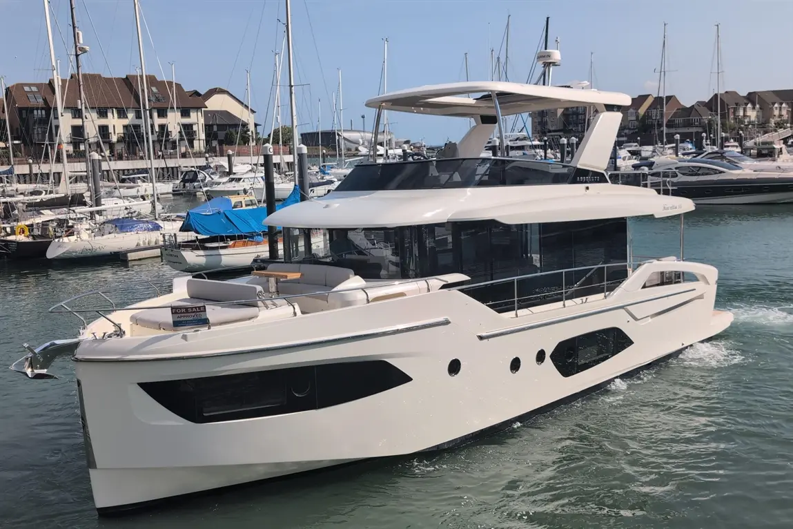 A luxury boat named 'Maritimo M51' is seen for sale, docked among other yachts in a marina on a sunny day.